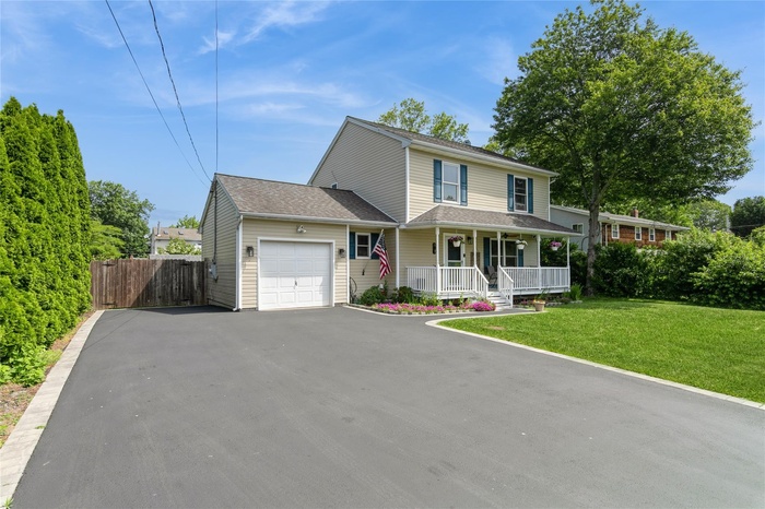 View of front of home with a porch, an attached garage, and asphalt driveway