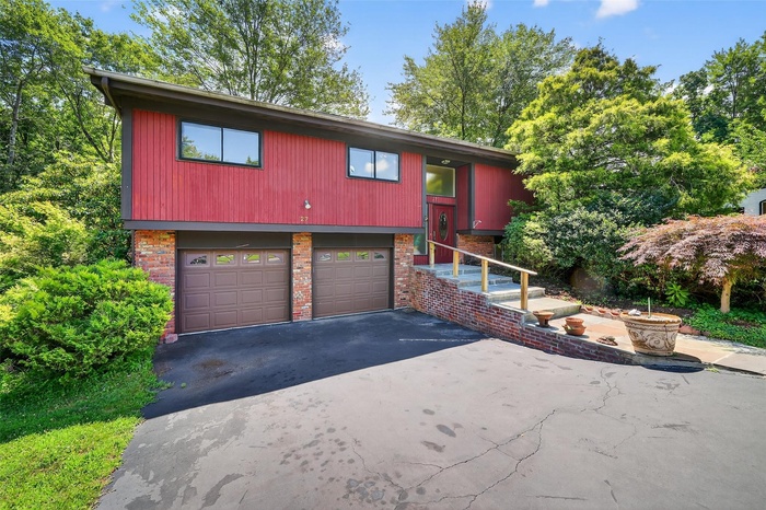 Split foyer home featuring an attached garage, driveway, and brick siding