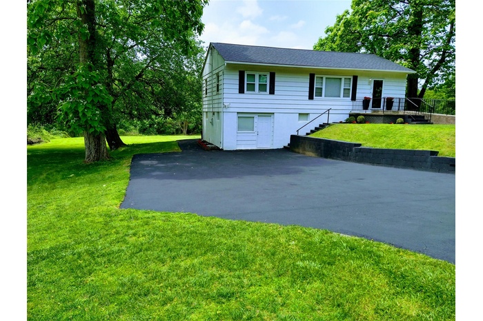 View of front of property featuring asphalt driveway and a front lawn