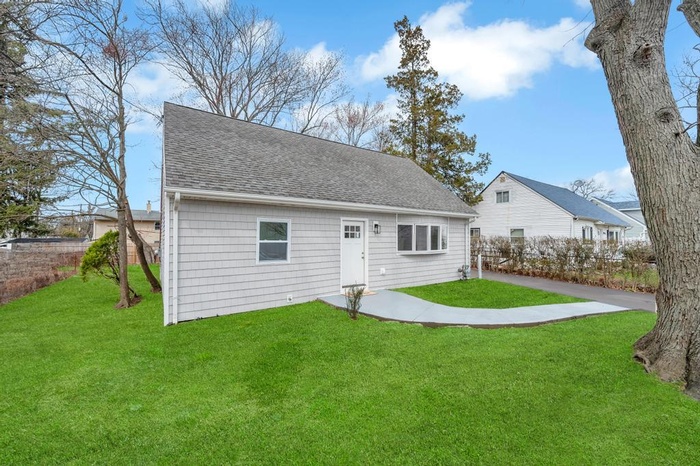 Rear view of property featuring a shingled roof and a yard