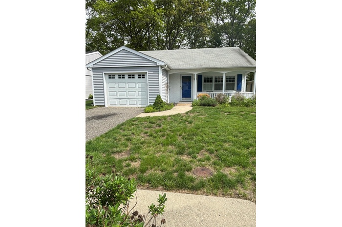 Ranch-style home featuring driveway, covered porch, a front yard, and an attached garage