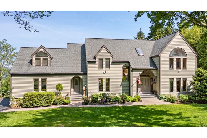 View of front facade featuring a front lawn and a shingled roof