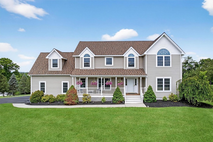 View of front of home featuring covered porch, a front yard, and a shingled roof