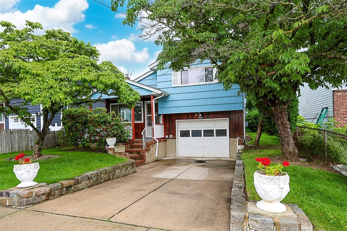 Tri-level home featuring an attached garage and driveway