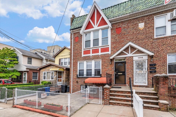 View of front facade with a gate, brick siding, a fenced front yard, and a tiled roof