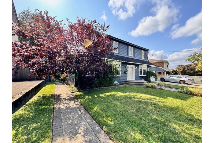 View of front of home with a front yard, fence, and a shingled roof