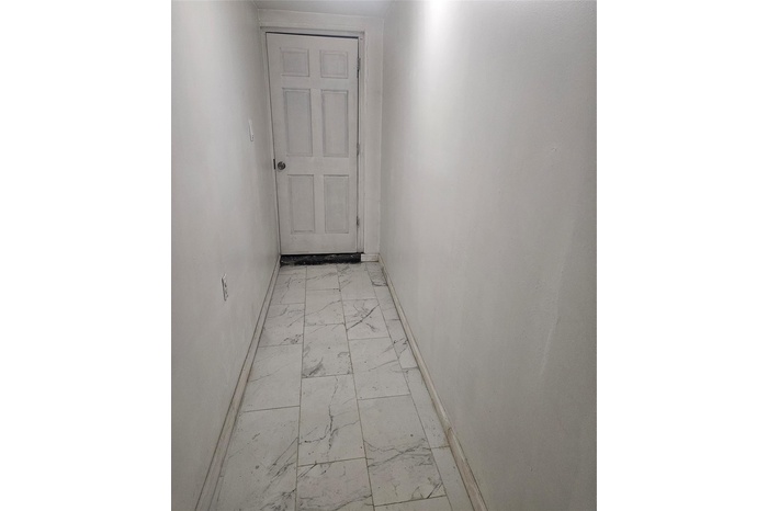 Hallway with light marble finish flooring and baseboards