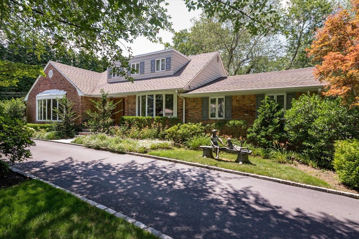 View of front of home featuring brick siding and roof with shingles