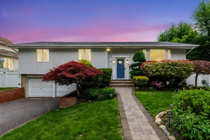 Raised ranch with driveway, an attached garage, and roof with shingles