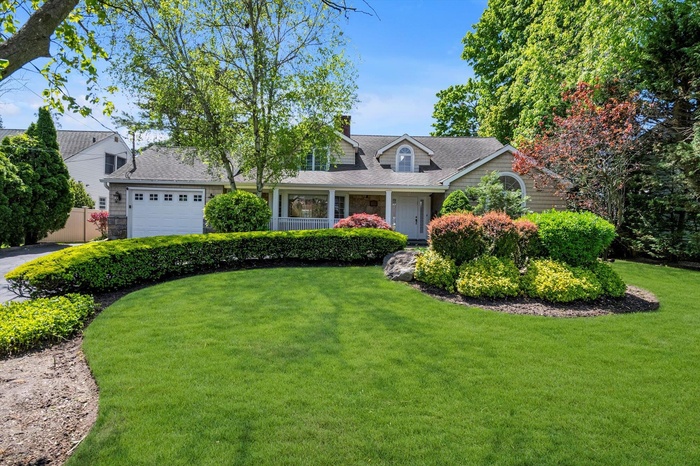 View of front facade with an attached garage, a front lawn, and a Porch