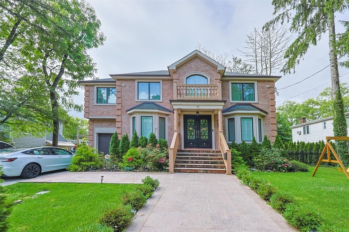 View of front of home featuring french doors, brick siding, and a balcony