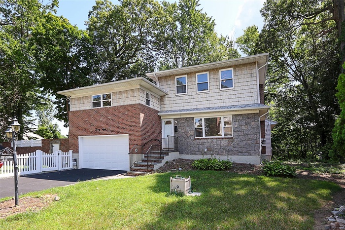 View of front of property featuring driveway, a garage, and stone siding