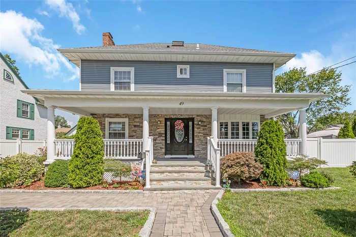 Traditional style home featuring a chimney, covered porch, and stone siding