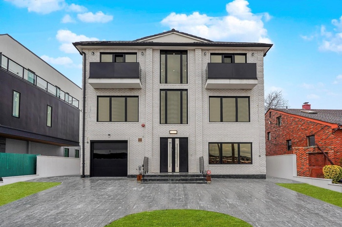View of front of property with driveway, an attached garage, and brick siding