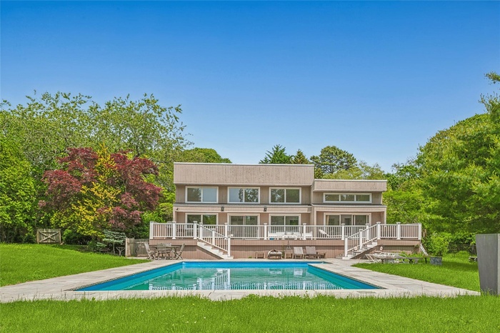 Rear view of house with stairs, a wooden deck, and an outdoor pool