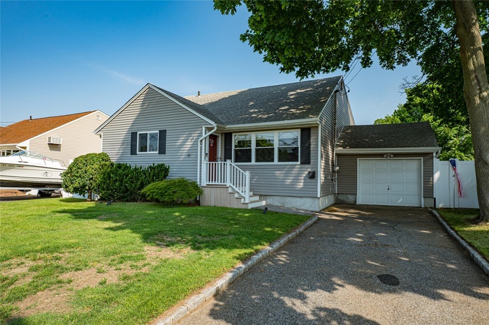View of front of property featuring asphalt driveway, an attached garage, and roof with shingles