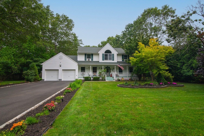 View of front of house featuring a porch, an attached garage, asphalt driveway, and a front lawn