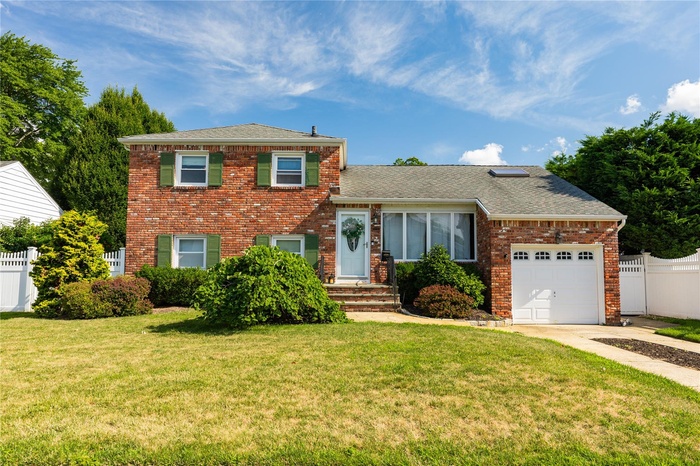Split level home featuring brick siding, a shingled roof, driveway, and an attached garage