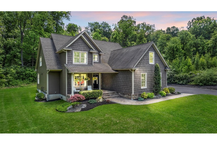 Craftsman-style home featuring a shingled roof, covered porch, and a lawn