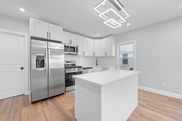 Kitchen featuring stainless steel appliances, light countertops, white cabinets, light wood-type flooring, and recessed lighting