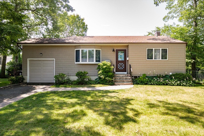Ranch-style home with a shingled roof, a garage, asphalt driveway, and a chimney