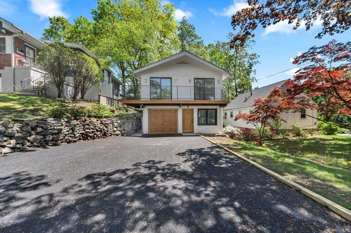 Contemporary house with an attached garage, asphalt driveway, and a balcony