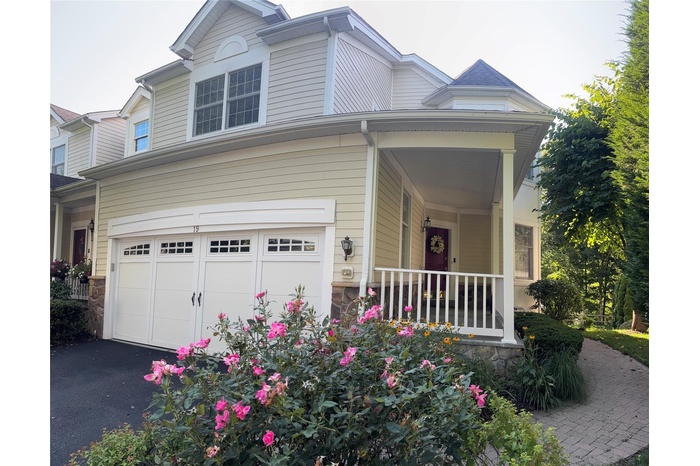 Traditional-style house with a porch, asphalt driveway, and a garage
