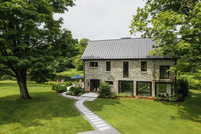Back of property featuring stone siding, a lawn, a metal roof, and a standing seam roof