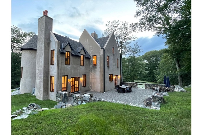 Back of property with a chimney, roof with shingles, and a patio