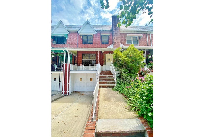 View of property featuring brick siding, driveway, and an attached garage