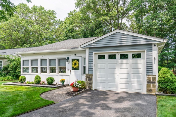 Ranch-style house featuring a garage, driveway, stone siding, board and batten siding, and a front yard
