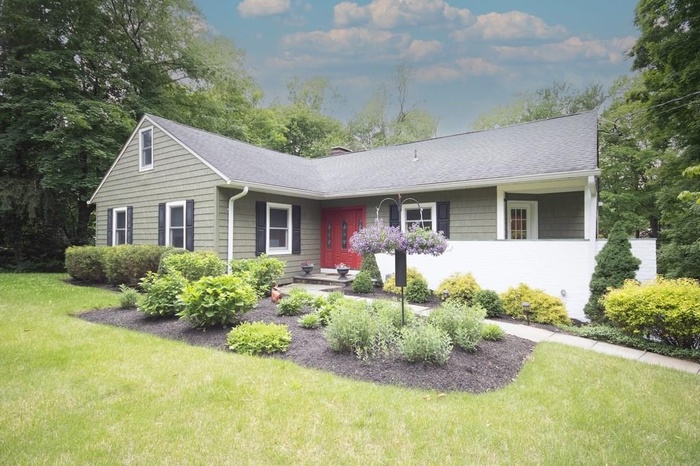 Ranch-style house with a front lawn, roof with shingles, and a chimney