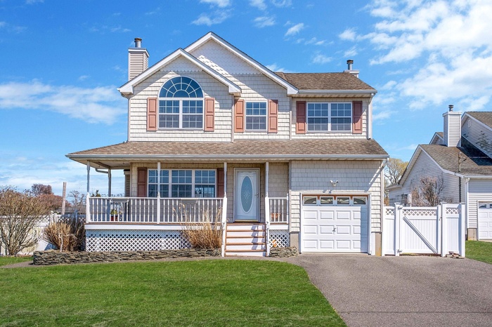 Traditional home featuring a chimney, aphalt driveway, a porch, a front yard, and a gate