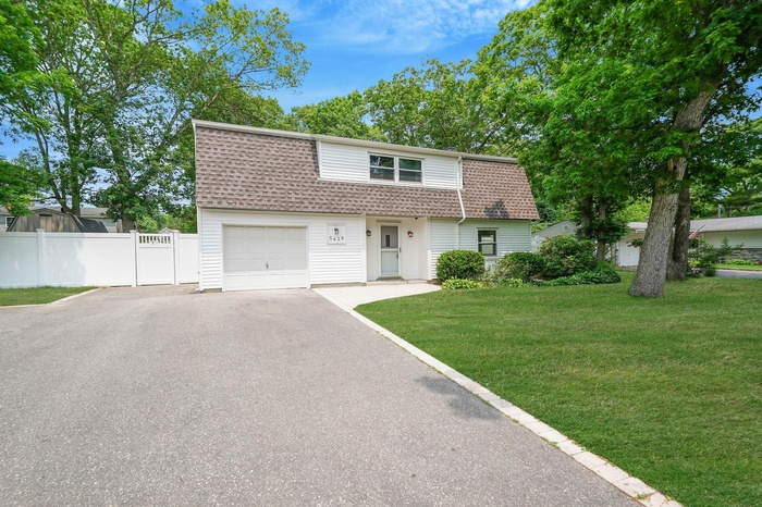 Dutch colonial featuring roof with shingles, driveway, and a garage