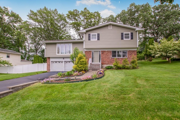 Split level home featuring brick siding, a garage, and asphalt driveway