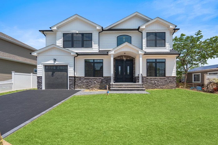 View of front of property with stone siding and asphalt driveway