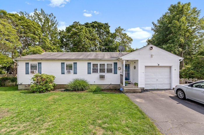 Single story home with driveway, an attached garage, and a front yard