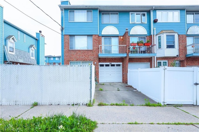 Townhome / multi-family property with an attached garage, brick siding, driveway, and a chimney
