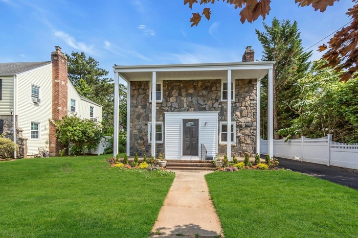 View of front facade with stone siding and a chimney