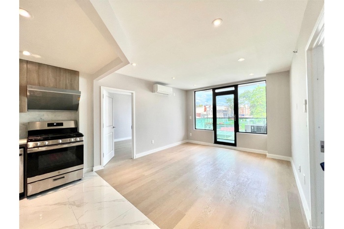 Kitchen with stainless steel range with gas cooktop, ventilation hood, an AC wall unit, recessed lighting, and baseboards