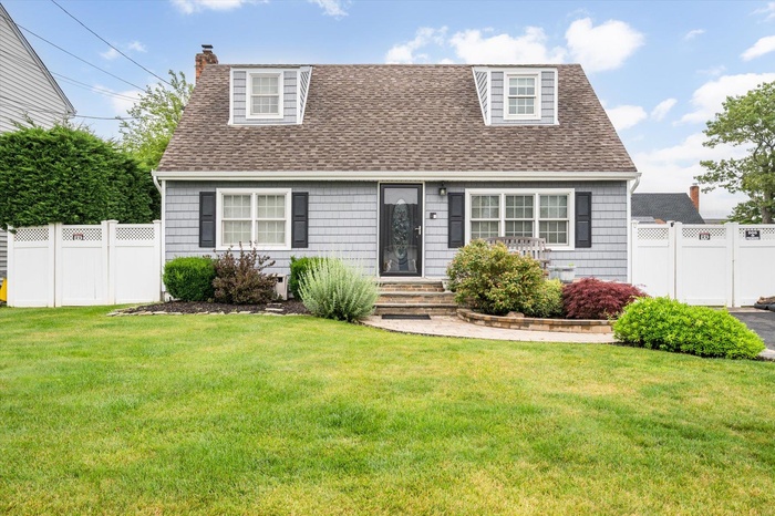 Cape cod house featuring roof with shingles and a chimney