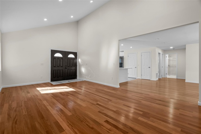 Foyer entrance featuring high vaulted ceiling and light hardwood / wood-style flooring