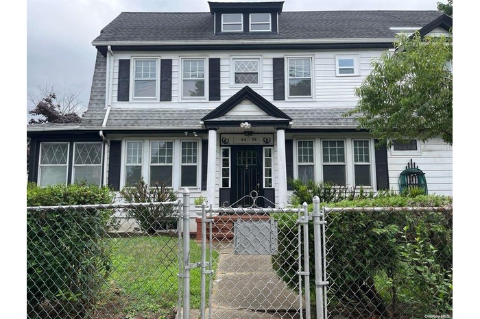View of front facade with a fenced front yard, a gate, and a shingled roof