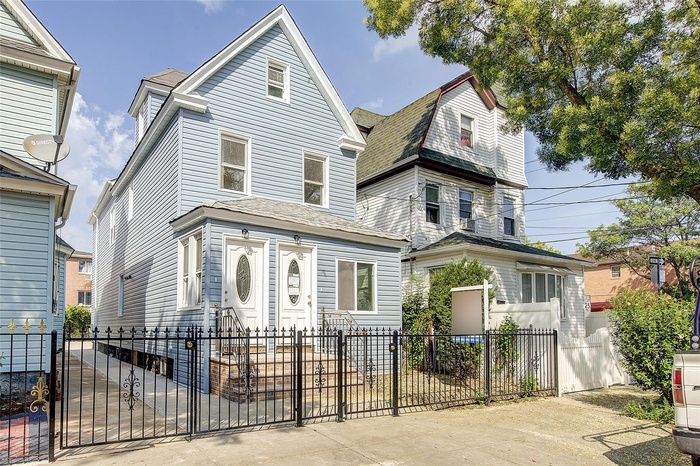 View of front of home featuring a fenced front yard, a gate, and a shingled roof