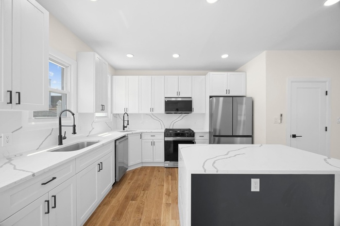 Kitchen with light wood-type flooring, white cabinetry, stainless steel appliances, and a sink