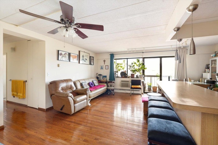 Living area featuring wood finished floors, ceiling fan, and a baseboard radiator