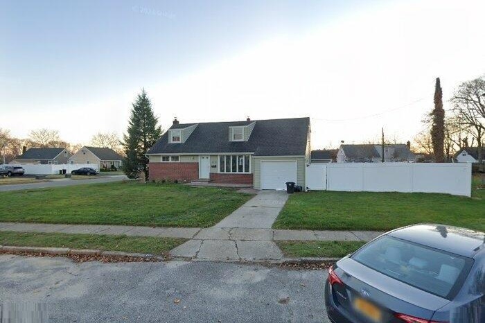 Cape cod-style house with a garage, fence, and a front lawn