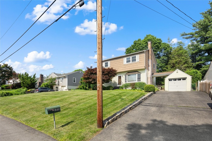 Colonial home with an outdoor structure, driveway, and a detached garage