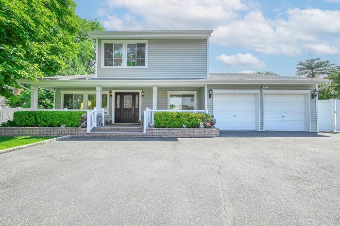 View of front facade featuring an attached garage, driveway, and covered porch