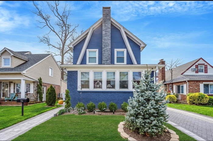 Dutch colonial with a front lawn, a chimney, a gambrel roof, and brick siding